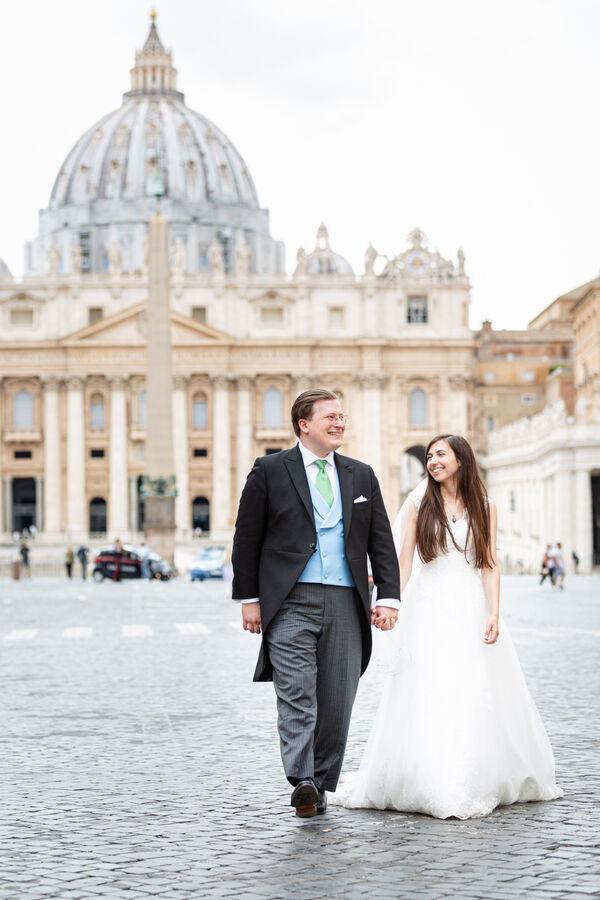 Sposi Novelli hand in hand walking down Via della Conciliazione with the Vatican in the background