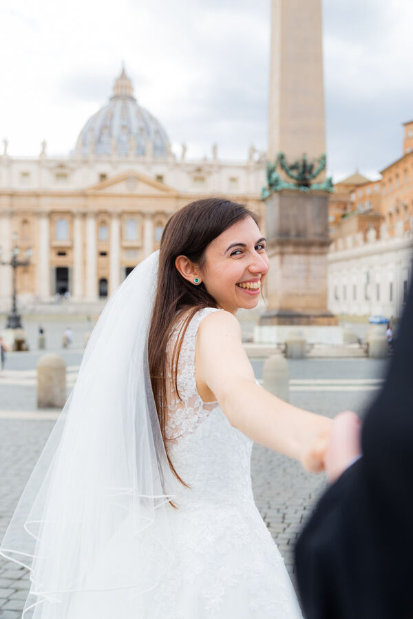 Bride pulling the groom's hand in Saint Peter's square